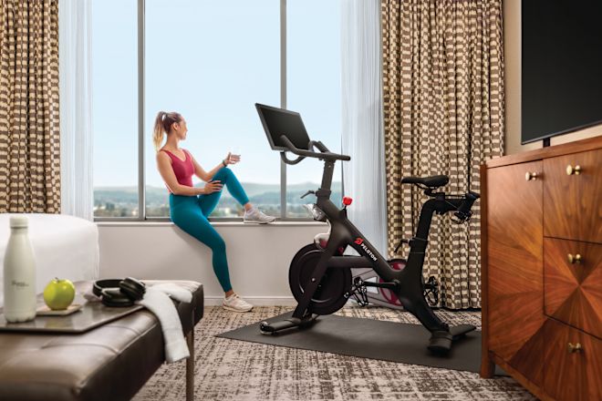 woman sitting on window sill in guestroom near peloton bike