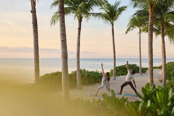 Mann und Frau praktizieren Yoga am Strand