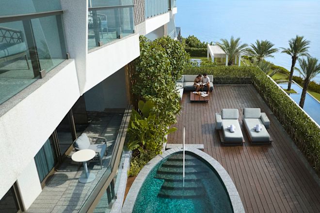 Mann und Frau entspannen sich auf der Terrasse ihrer Suite mit eigenem Swimmingpool