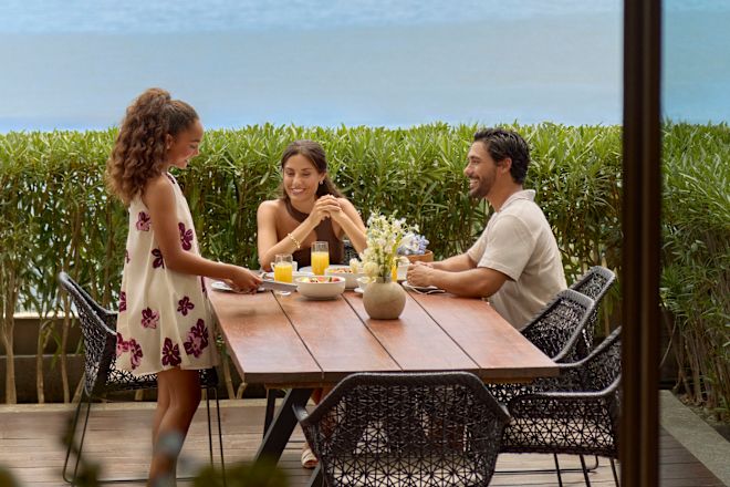 Mutter, Vater und Tochter genießen Frühstück auf der Terrasse ihrer Suite