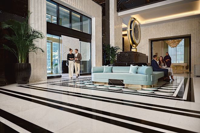 ホテルの入り口から目覚まし時計を備えたロビーエリアへ足を踏み入れる男女