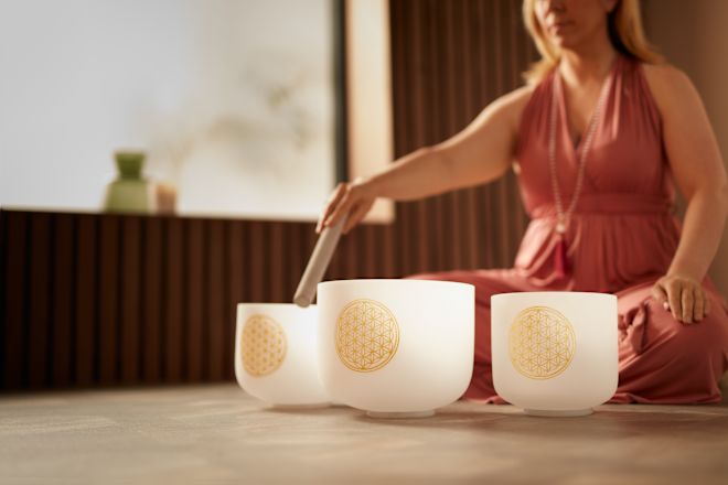 Frau, die im Spa mit Singsing-Bowls entspannende Geräusche macht