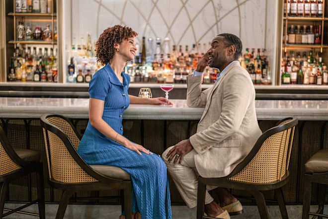 Pria dan wanita tersenyum saat mereka bersantai di bar sambil minum-minum