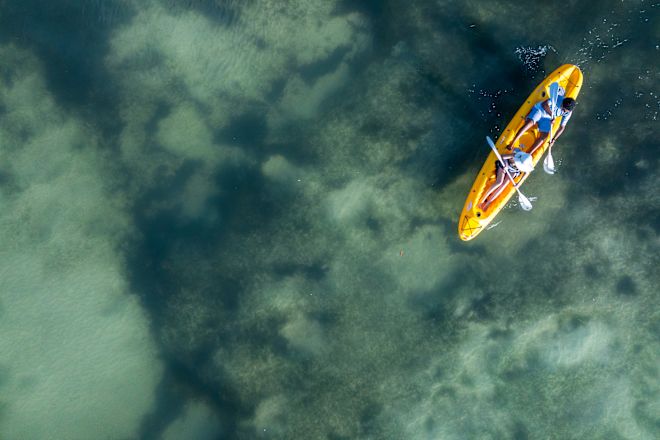 Luftaufnahme des Meeres und zwei Personen auf dem gelben Kajak