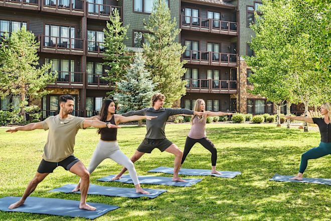 Un grup de oameni care practică yoga în aer liber