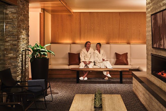 Cuplu relaxându-se în zona de zi, lângă șemineu, la centrul spa