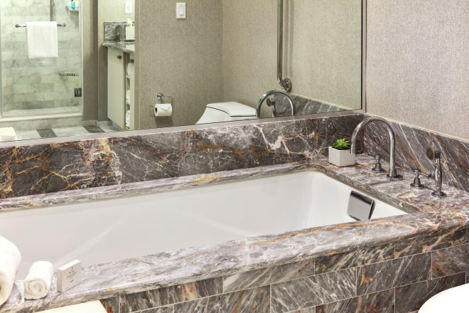 Gästebadezimmer mit marmorner Badewanneneinfassung und begehbarer Dusche