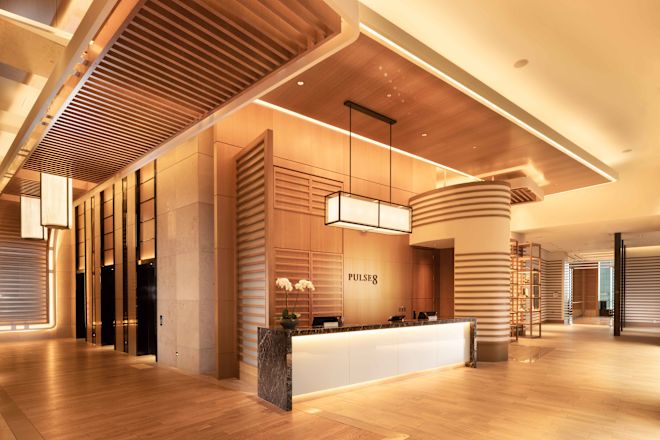 Pulse8 Reception desk. Decorative wood paneling and warm, modern lighting complete the space.