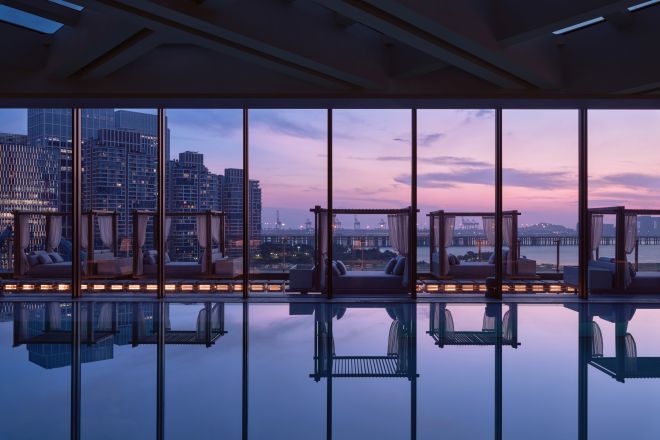 Swimming pool with large window to view of sunset