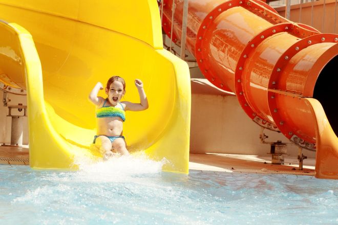 Happy little girl on waterslide of water park