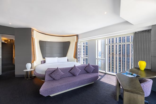 Suite with Round Bed, End of Bed Bench, Work Desk, and Outside View