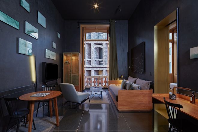 Guestroom lounge area with sofa, TV, and double doors open to balcony.