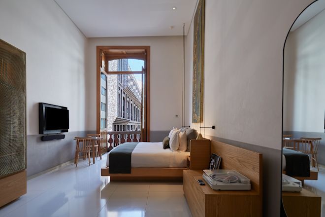 Guestroom with bed, bench seat, and double doors open to balcony.