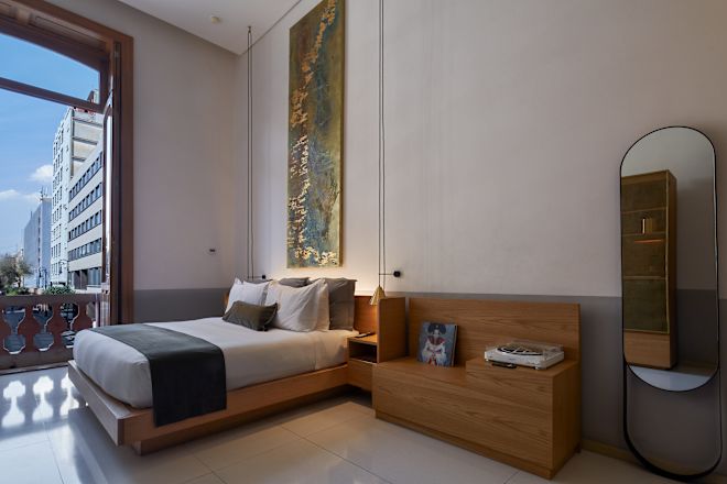 Guestroom with bed, double doors open to balcony and bench seat.