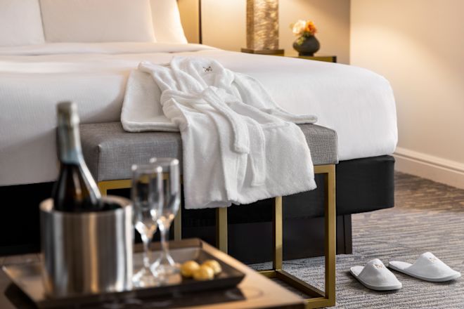 Bathrobe on a bench and a tray with champagne and flutes on table.