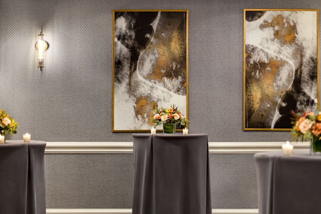 A hotel meeting room, the Herald Square set up for a social with small round tables covered with linens.