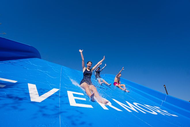 Üç kişi su kayağından inerken kollarını gergin tutarak gülüyor