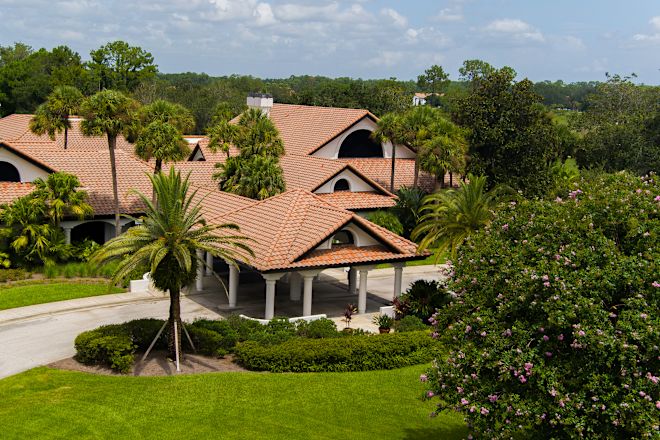 Giriş, garaj yolu ve ağaçlar bulunan binanın havadan çekilmiş fotoğrafı