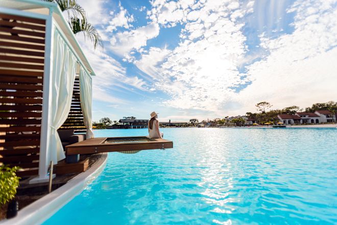 Balkonun dış cephesinde su manzarasına bakan kadın