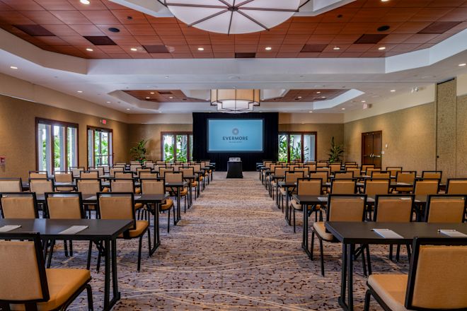 Masalar, sandalyeler ve projeksiyon perdesi bulunan toplantı odası