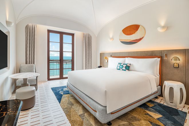 大きなベッド1台を配した客室とバルコニーからのオーシャンビュー