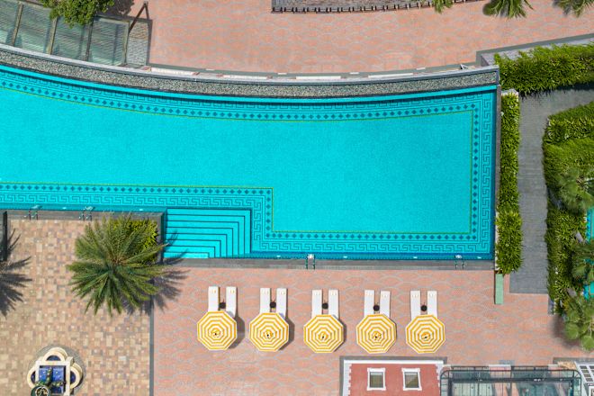 ヤシの木とラウンジチェアを備えたプールエリアの上空からの眺め