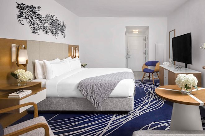 Large Bed in Guest Room with HDTV Soft Chair and Small Round Table