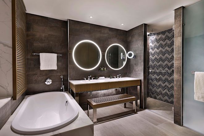 キングベッドを配した1ベッドルームバスルームのシンクとバスタブ