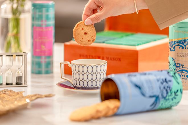 person dunking biscuit in tea cup with biscuit in foreground