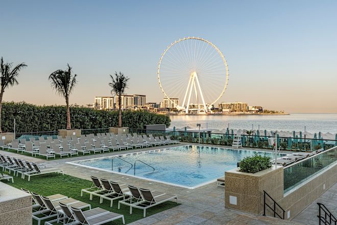 Piscină exterioară cu șezlonguri din jur și roată din ferigă