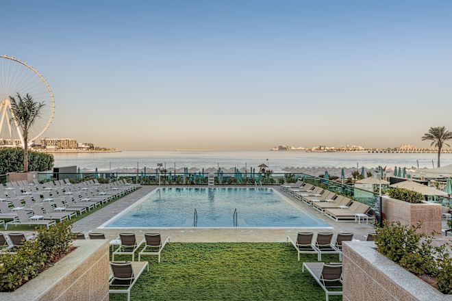 Piscină exterioară cu șezlonguri, vedere spre mare și rotiță de fier