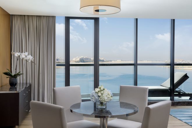 Table de salle à manger et balcon d'une suite exécutive avec très grand lit