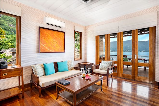 Khu vực thư giãn với ghế sofa, ghế và cửa gỗ bằng kính dẫn đến ban công.