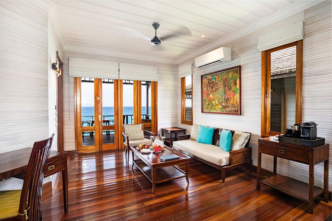 Ruang tamu dengan pintu menuju balkon dan pemandangan laut.