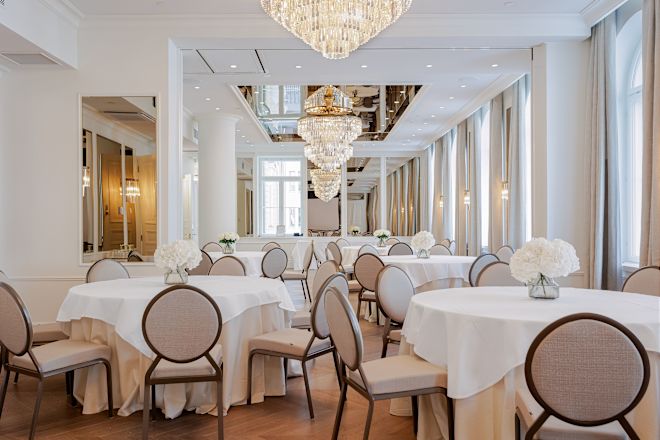 قاعة كبيرة مجهزة بطاولات مستديرة، وترتيبات زهور، وثريات