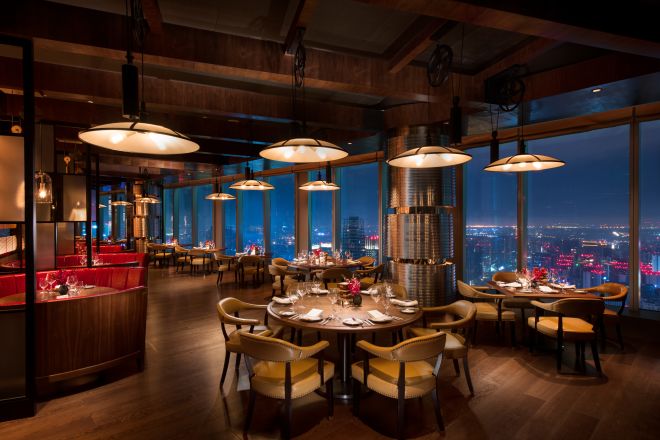 Limited Edition Grill restaurant with dining tables, chairs, dining amenities, and floor-to-ceiling windows with city view at night