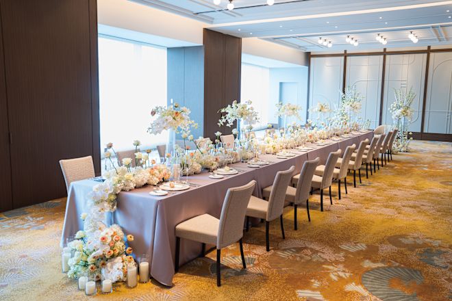Long table decorated with multi-colored flowers, and set up for reception dinner.