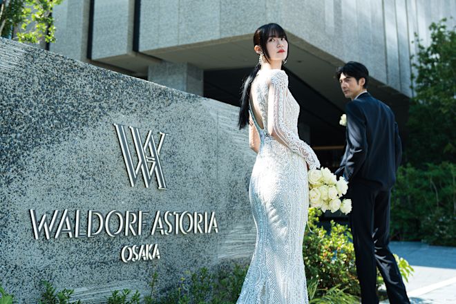 Bride in her wedding gown and groom in tuxedo standing in front of the hotel signage.