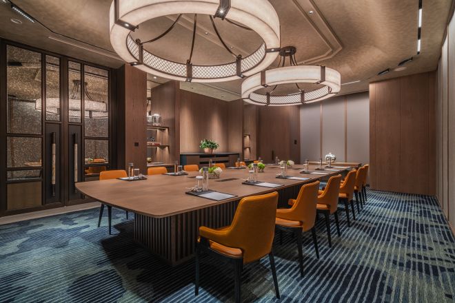 長いテーブルとオレンジ色の椅子を備えたミーティングルーム