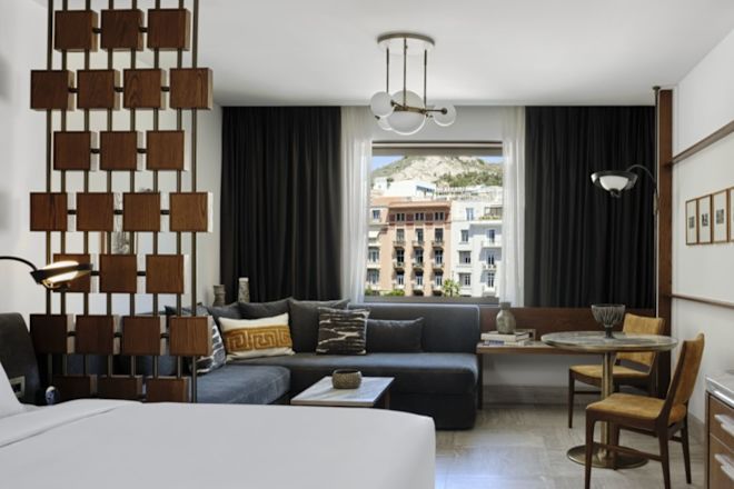 Loungebereich im Zimmer mit komfortablen Sitzgelegenheiten, Tischen und Fernseher