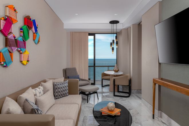 Ocean front suite living room with chairs, sofa and wall mounted TV