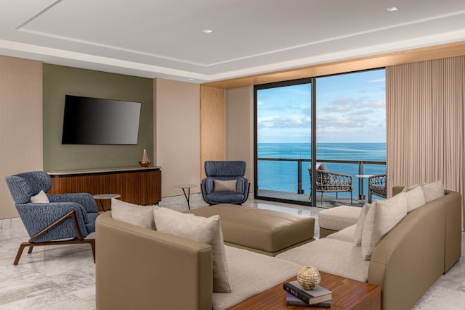 Wohnzimmer der Suite mit Sofa, Stühlen, Balkon und Wandfernseher