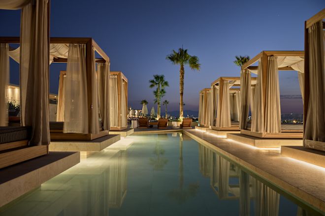 Cabanas in Outdoor Pool Area with Palm Trees at Night