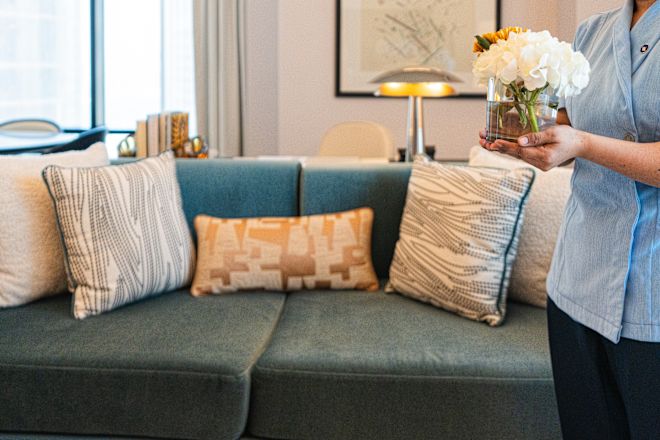 ホテルのスイートのリビングルームで白い花々を片手に洗面台を持つ女性