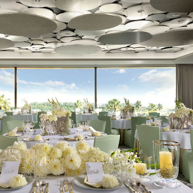 Bröllopsbord med blommor, ljus och platsinställningar på rummet med stora fönster