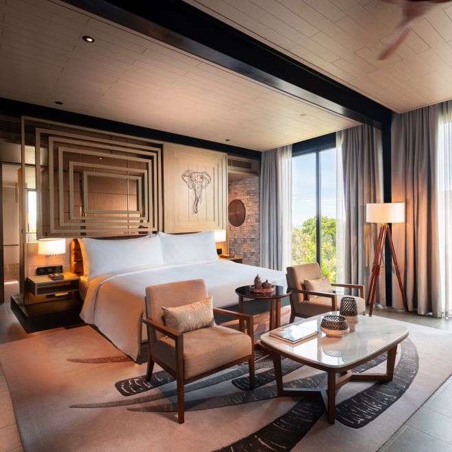 Cama grande en una habitación con área de estar y ventana amplia