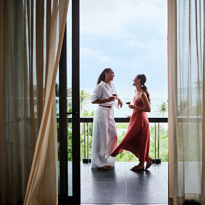 Two women standing on balcony with drinks