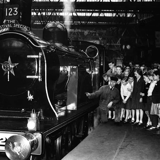 Old shot of station staff showing people train