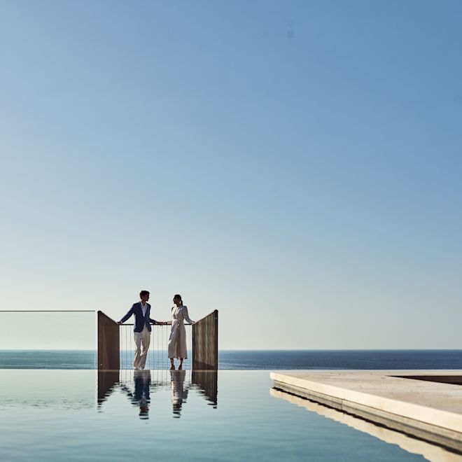 Couple Standing by the Infinity Pool Area with View of the Sea