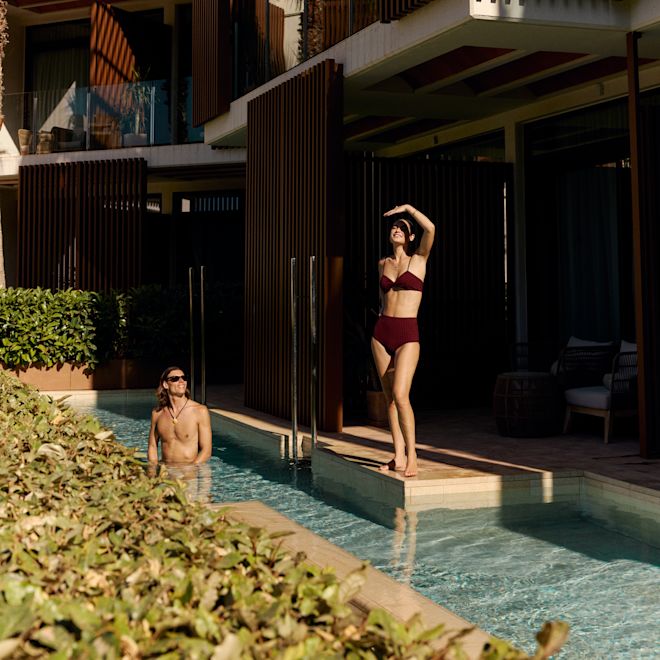 Mann und Frau im privaten Swimmingpool, Frau schirmt ihre Augen vor der Sonne ab